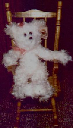 pink bear sitting in a wooden rocking chair
